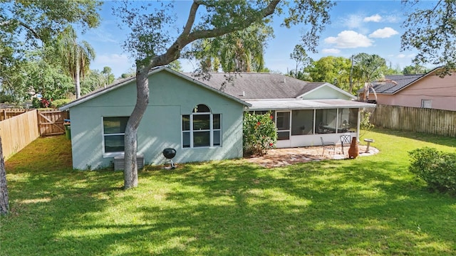 back of house featuring roof with shingles, a lawn, a sunroom, a fenced backyard, and stucco siding