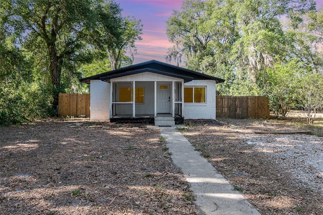 bungalow-style house with covered porch, fence, and stucco siding