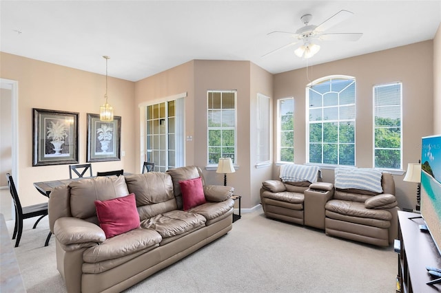 living area featuring light carpet, a ceiling fan, and baseboards