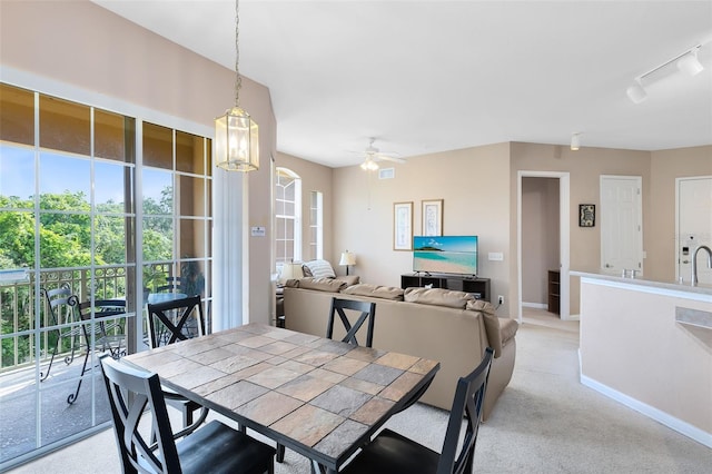 dining space with baseboards, light colored carpet, ceiling fan, and rail lighting