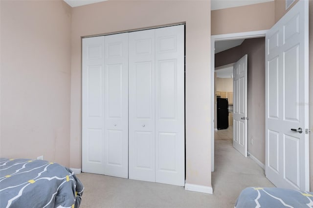bedroom with light carpet, baseboards, and a closet