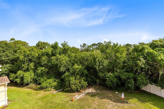 view of green lawn featuring a wooded view