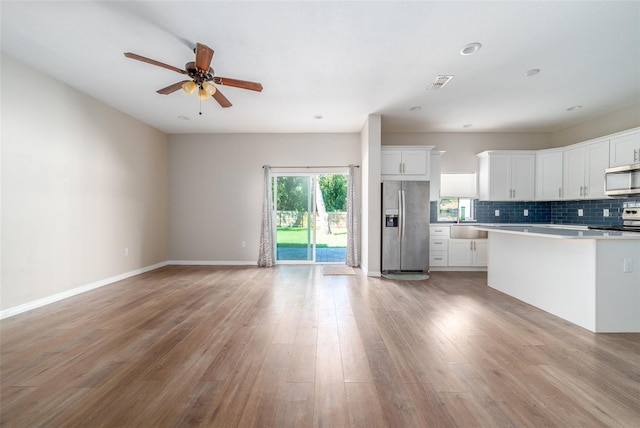 kitchen with decorative backsplash, stainless steel appliances, light wood-type flooring, light countertops, and white cabinets