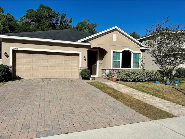 ranch-style home with an attached garage, decorative driveway, and stucco siding