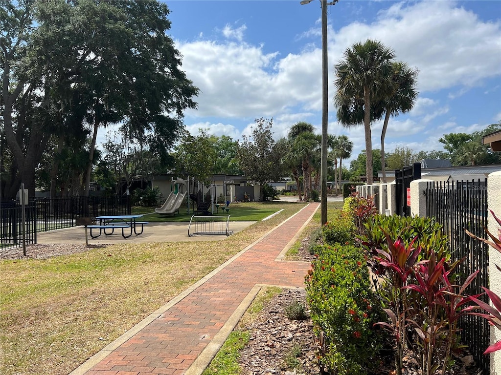 surrounding community with a lawn, playground community, and fence