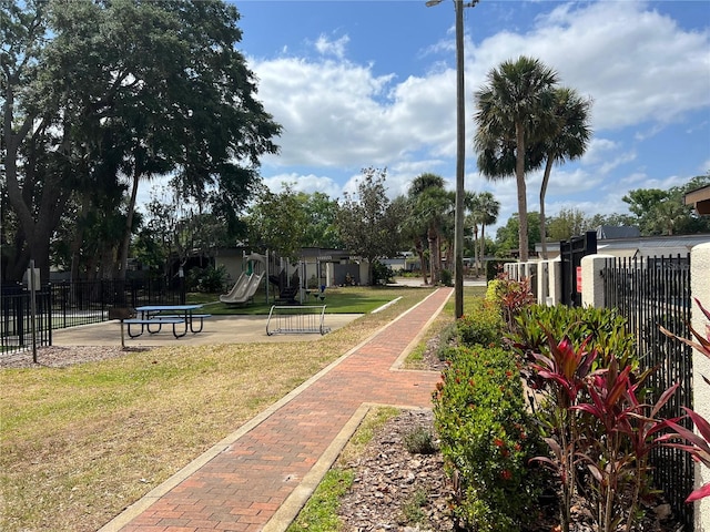 surrounding community with a lawn, playground community, and fence