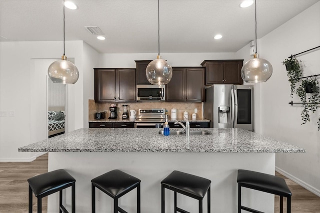 1801 Nice Ct, Kissimmee, FL 34747 - kitchen with appliances with stainless steel finishes, a sink, light wood-style flooring, a kitchen bar, and visible vents