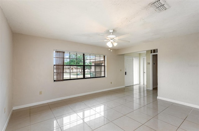 spare room featuring light tile patterned floors, baseboards, a ceiling fan, and visible vents