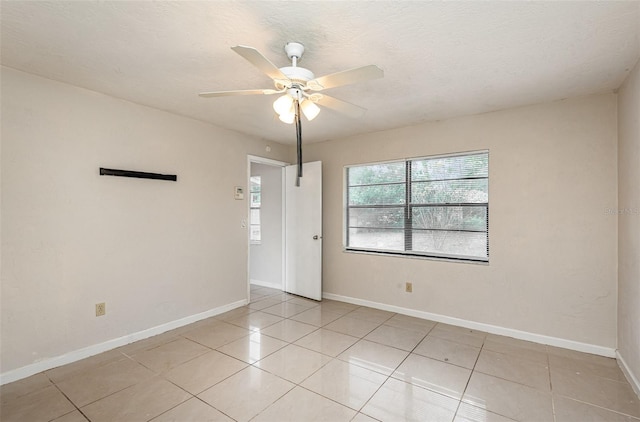 spare room with baseboards, a ceiling fan, and light tile patterned floors