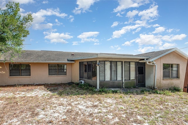 back of property with roof with shingles, a sunroom, and stucco siding
