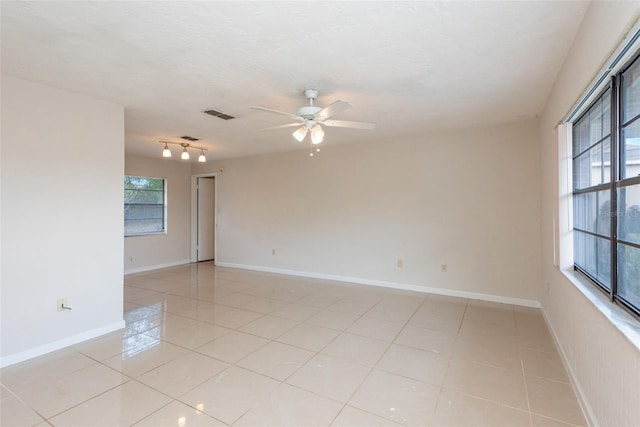 unfurnished room with baseboards, ceiling fan, visible vents, and light tile patterned floors