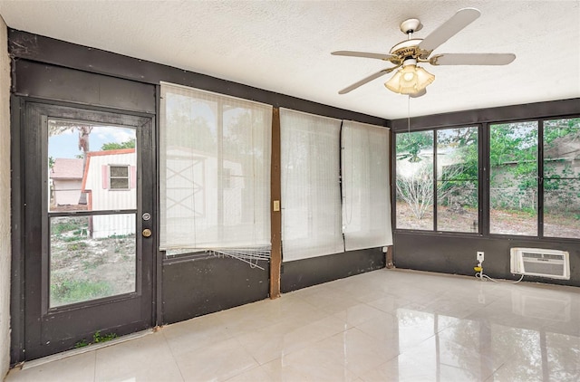 unfurnished sunroom featuring plenty of natural light, a wall unit AC, and a ceiling fan