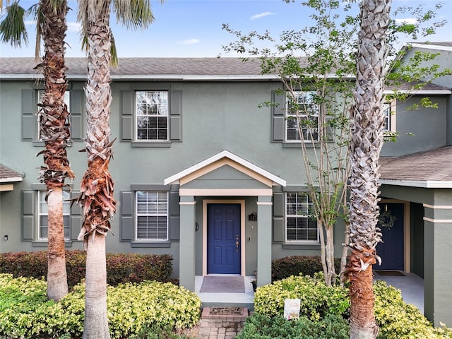view of property with a shingled roof and stucco siding