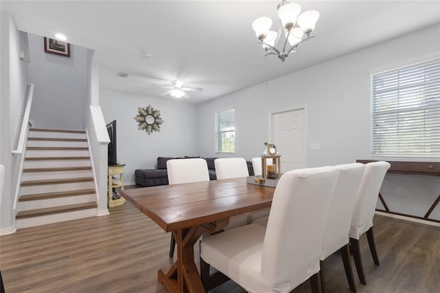 dining room featuring visible vents, stairs, wood finished floors, baseboards, and ceiling fan with notable chandelier