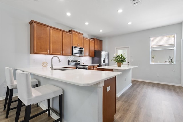 kitchen with a sink, brown cabinetry, a center island, stainless steel appliances, and visible vents