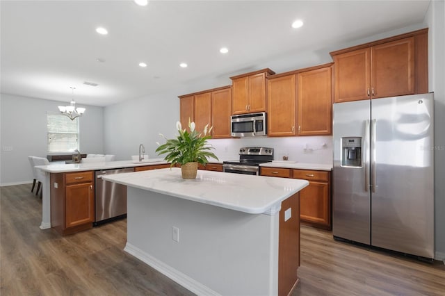 kitchen featuring a sink, brown cabinetry, stainless steel appliances, and a peninsula