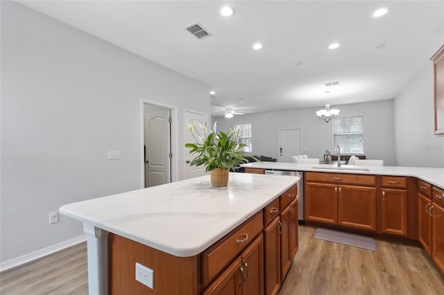 kitchen with dishwasher, a sink, a peninsula, light wood finished floors, and recessed lighting