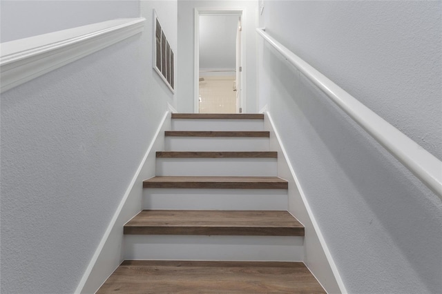 stairway with visible vents and wood finished floors