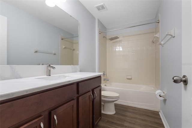 bathroom featuring visible vents, vanity, wood finished floors, toilet, and bathtub / shower combination