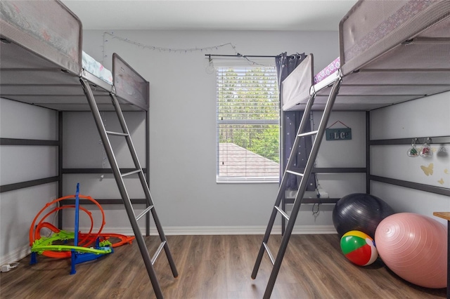 unfurnished bedroom featuring baseboards, multiple windows, and wood finished floors