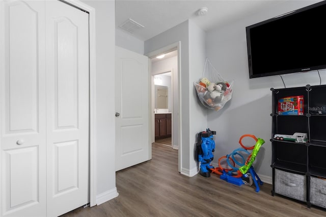 recreation room featuring baseboards, visible vents, and wood finished floors