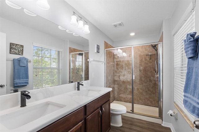 bathroom with a stall shower, visible vents, a sink, and wood finished floors