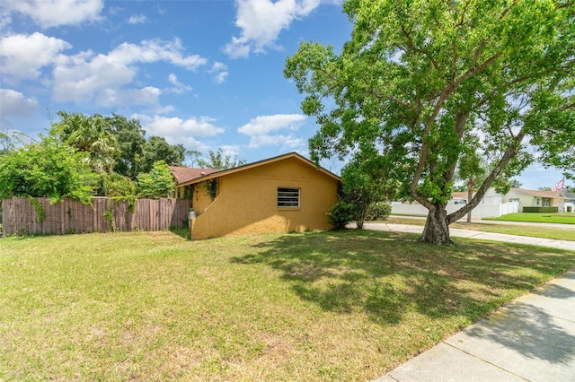 view of home's exterior with a lawn, fence, and stucco siding
