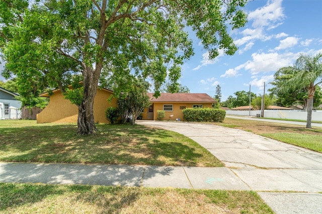 view of front facade featuring stucco siding, a front lawn, fence, and concrete driveway