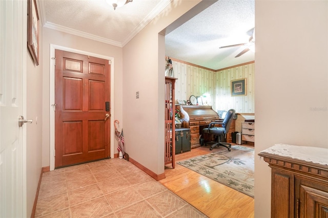 entrance foyer featuring crown molding, baseboards, ceiling fan, and a textured ceiling
