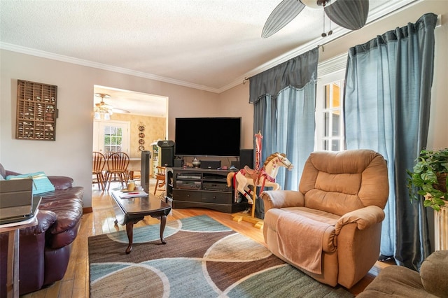 living area featuring a textured ceiling, ceiling fan, ornamental molding, and wood finished floors