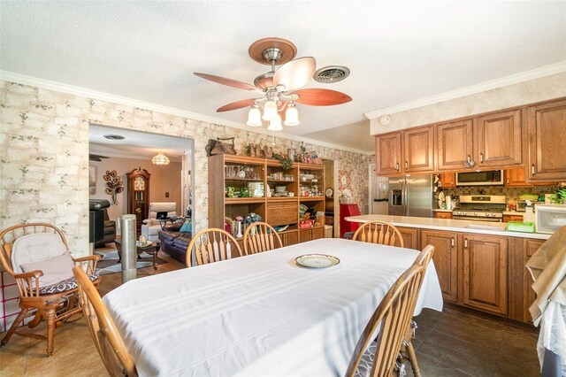 dining area featuring ceiling fan, wallpapered walls, dark tile patterned flooring, visible vents, and ornamental molding