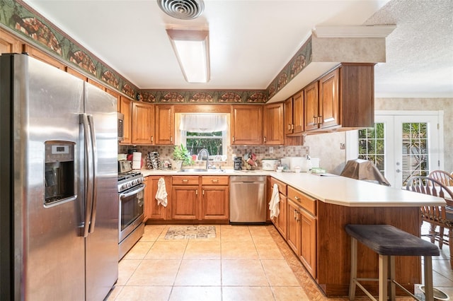 kitchen with a peninsula, a sink, appliances with stainless steel finishes, and a healthy amount of sunlight