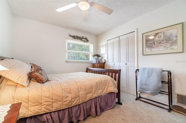 bedroom with carpet flooring, ceiling fan, a textured ceiling, visible vents, and a closet
