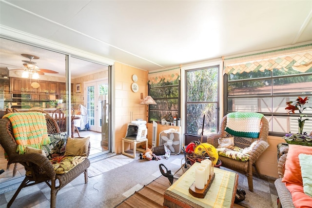 sunroom featuring a ceiling fan, wood finished floors, and an outdoor hangout area