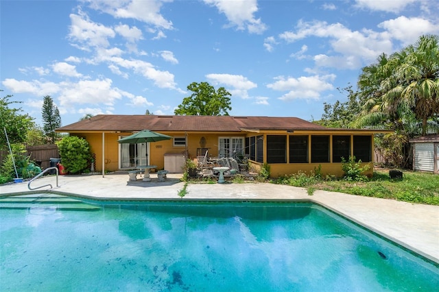 pool featuring a patio, fence, and a sunroom
