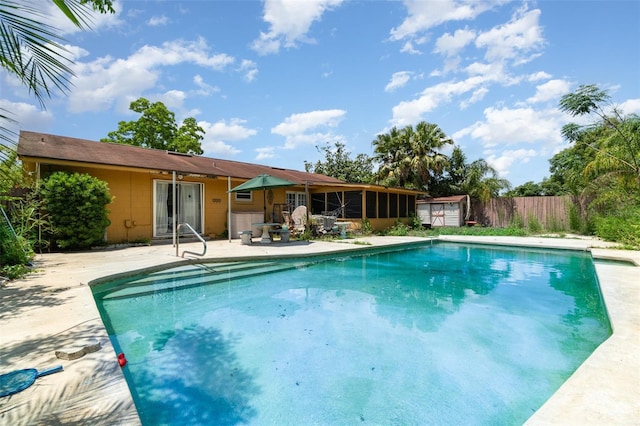 pool with an outbuilding, a sunroom, a patio area, fence, and a storage unit
