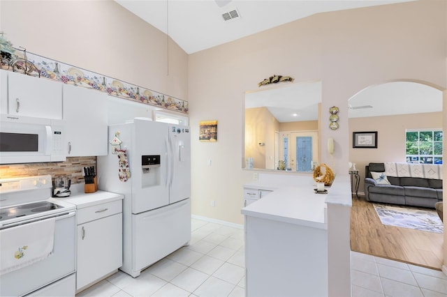 3661 Kingswood Ct, Clermont, FL 34711 - kitchen featuring white appliances, arched walkways, light countertops, a peninsula, and light tile patterned floors