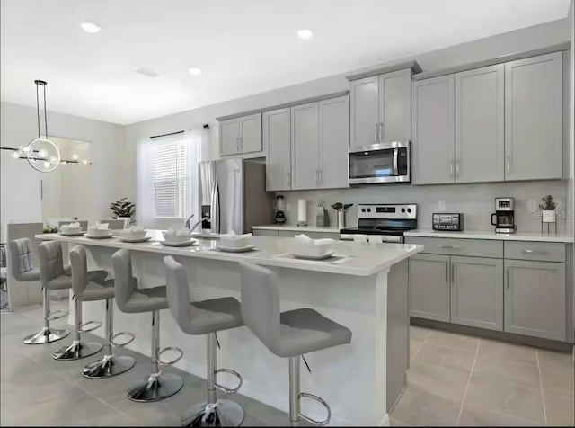 1929 Tropical Palms Cir, Kissimmee, FL 34747 - kitchen with light countertops, a breakfast bar area, gray cabinetry, and stainless steel appliances
