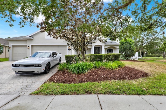 view of front facade with stucco siding, decorative driveway, and a garage