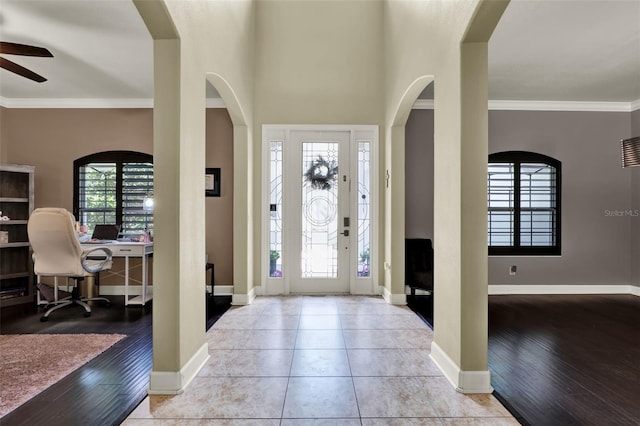 foyer featuring baseboards, ceiling fan, ornamental molding, and wood finished floors