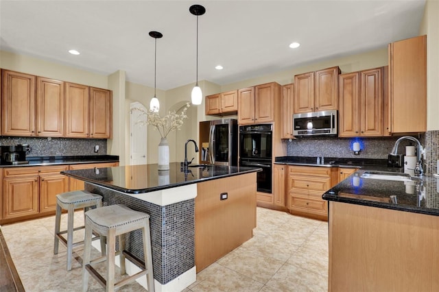 kitchen featuring appliances with stainless steel finishes, a sink, decorative light fixtures, decorative backsplash, and a kitchen bar