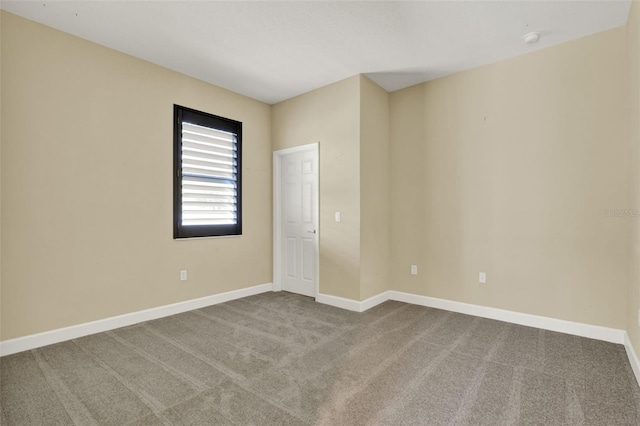 carpeted empty room featuring baseboards