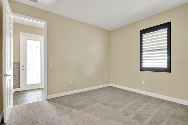 spare room with carpet floors, baseboards, and tile patterned floors