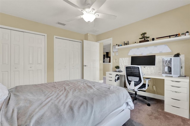 carpeted bedroom featuring visible vents, multiple closets, and ceiling fan
