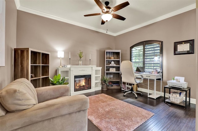 office space with dark wood-type flooring, crown molding, a glass covered fireplace, and ceiling fan