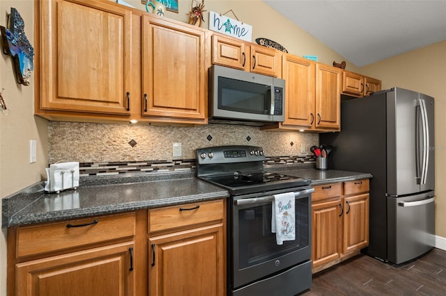 kitchen with dark countertops, backsplash, stainless steel appliances, and dark wood-type flooring