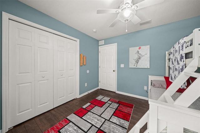 bedroom featuring visible vents, a closet, wood finished floors, baseboards, and a ceiling fan