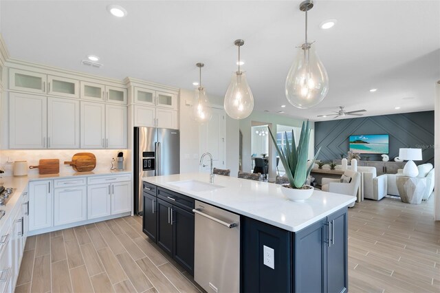 kitchen with appliances with stainless steel finishes, hanging light fixtures, a sink, light countertops, and a ceiling fan