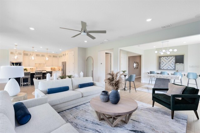 living room featuring ceiling fan, visible vents, baseboards, recessed lighting, and light wood-style flooring