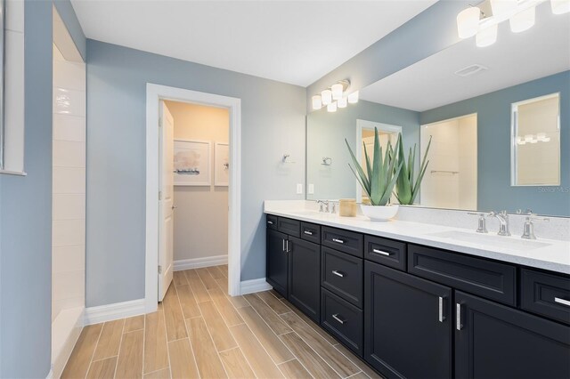 full bathroom with a sink, baseboards, and double vanity